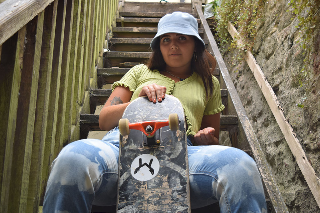Lucy sat on some stairs with her skateboard